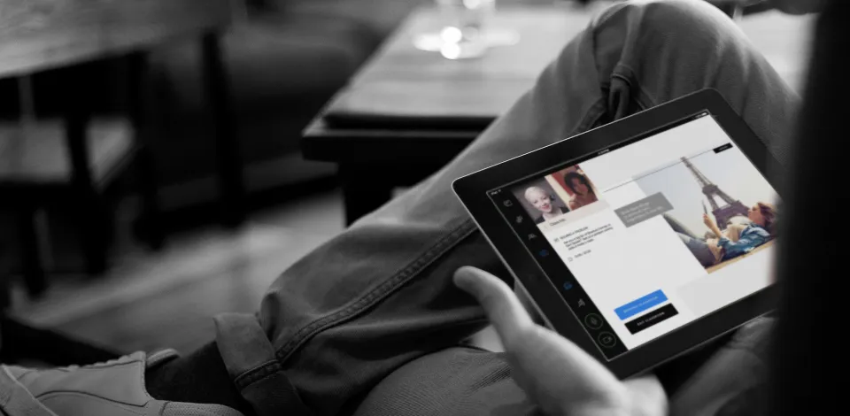 A person sitting with a tablet on their lap. The tablet shows the interface for a virtual english classroom.