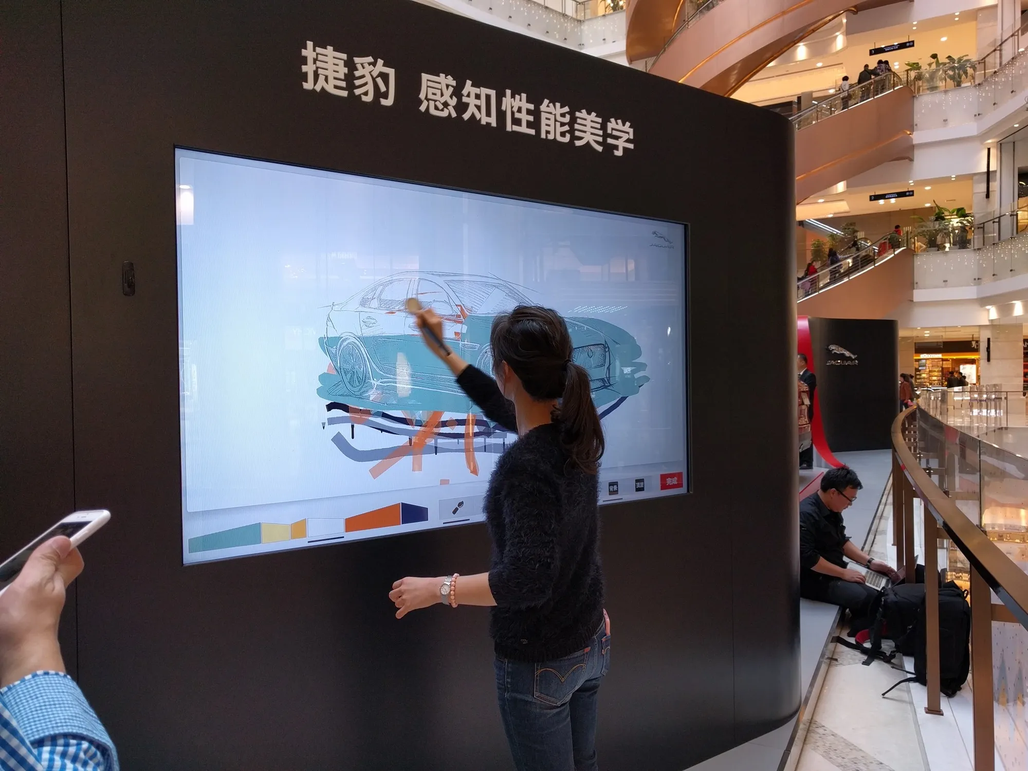 A woman adding color to a sketch of a Jaguar car